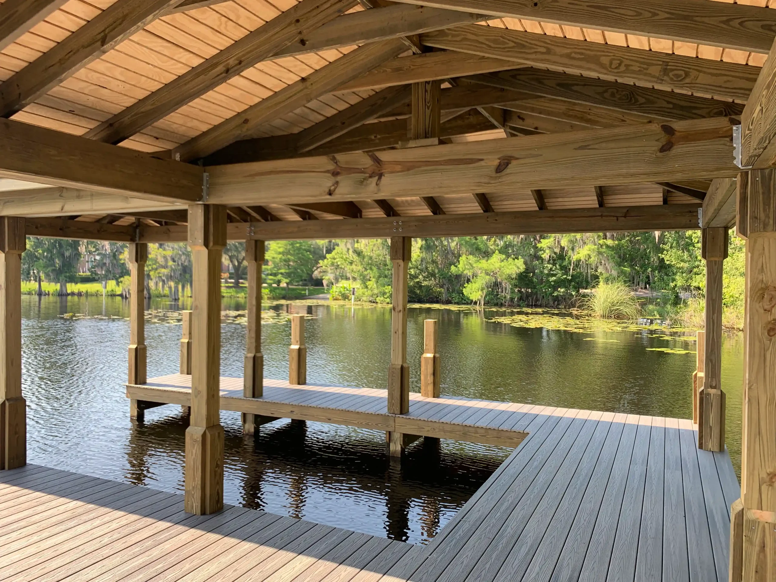 Rustic wooden dock structure with gabled roof over calm reflective water.
