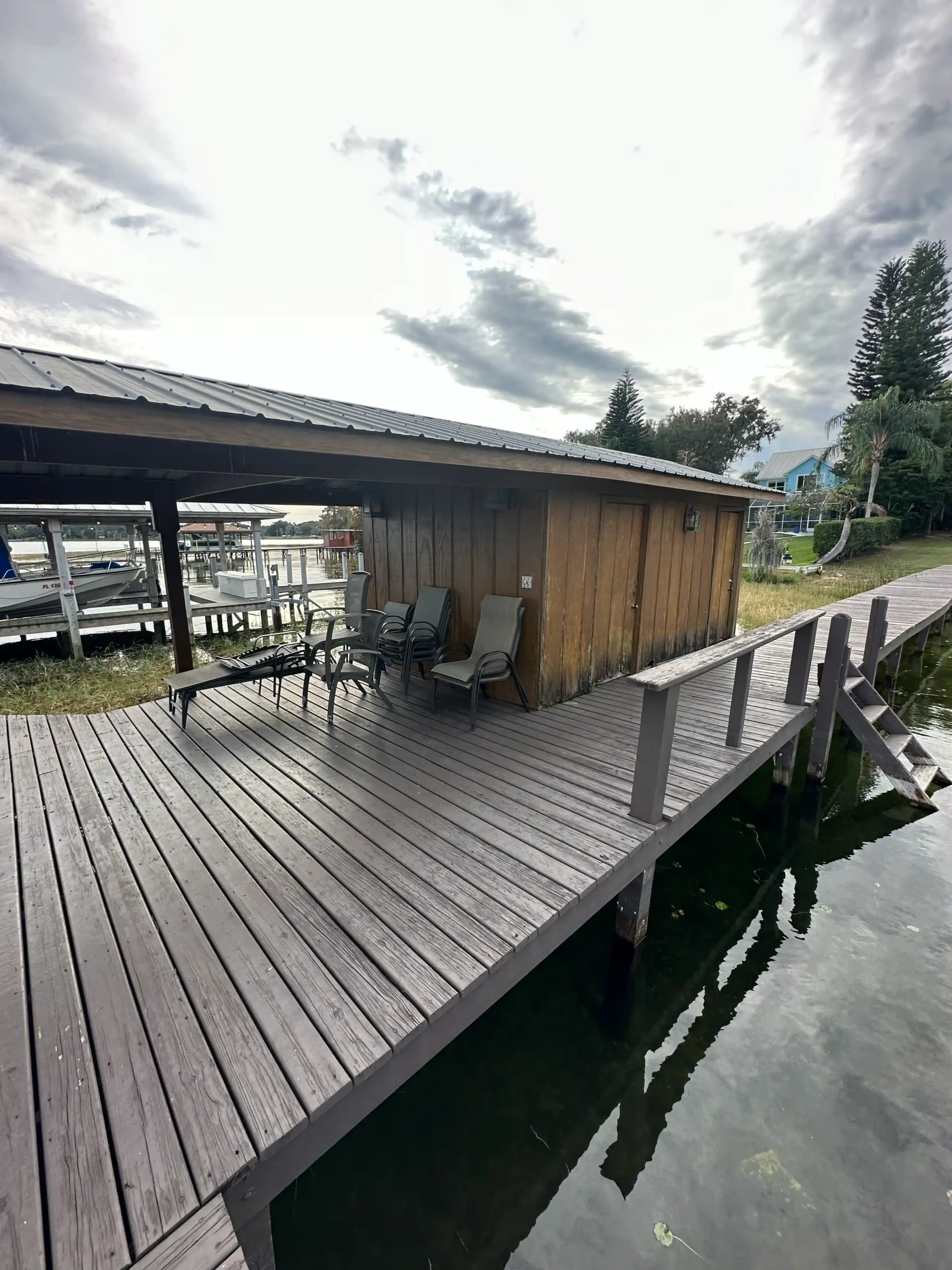 A rustic wooden dock with lounge chairs under a shed-style roof.