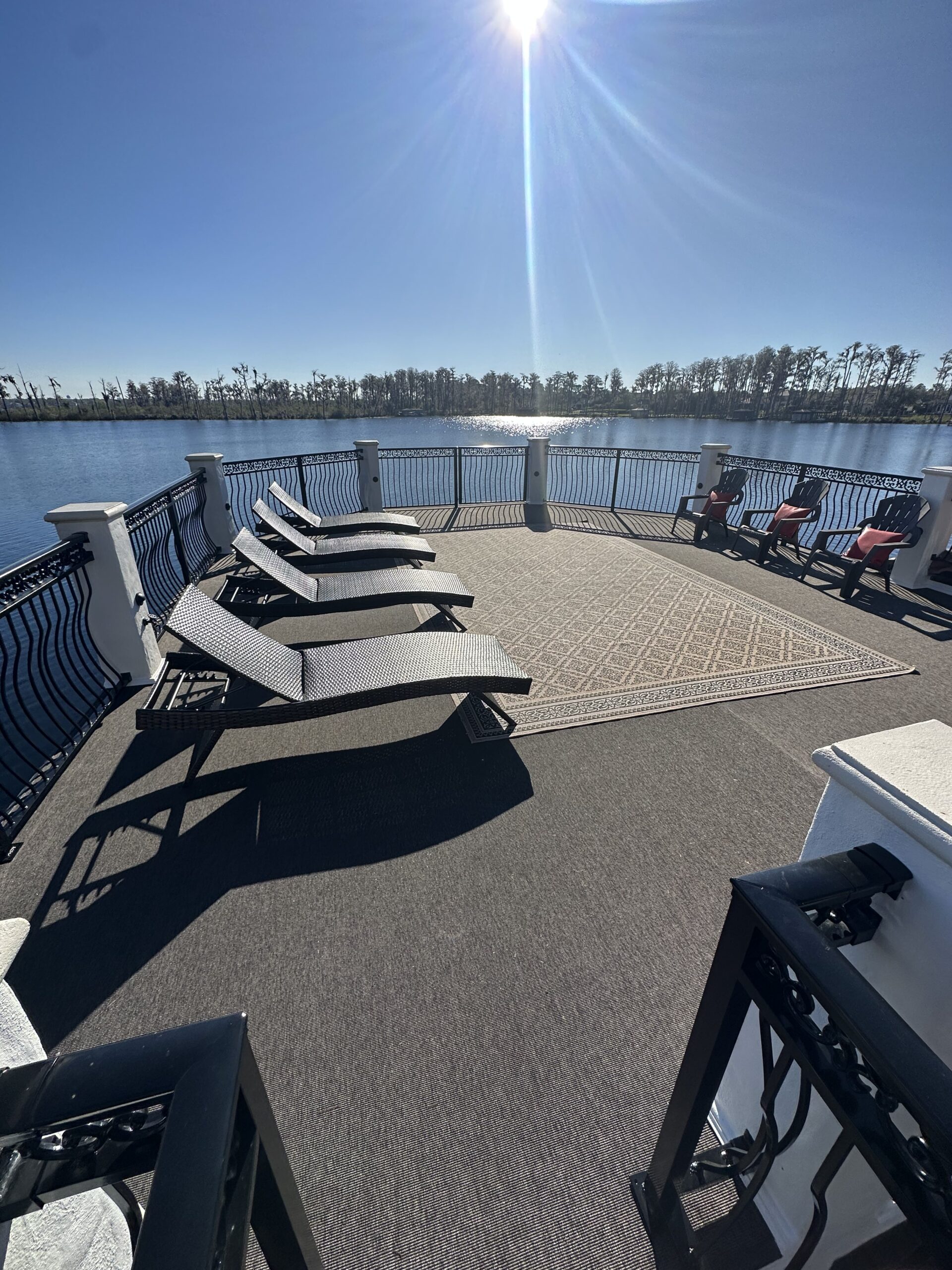 Rooftop deck on a dock with lounge chairs and lake view under sun.